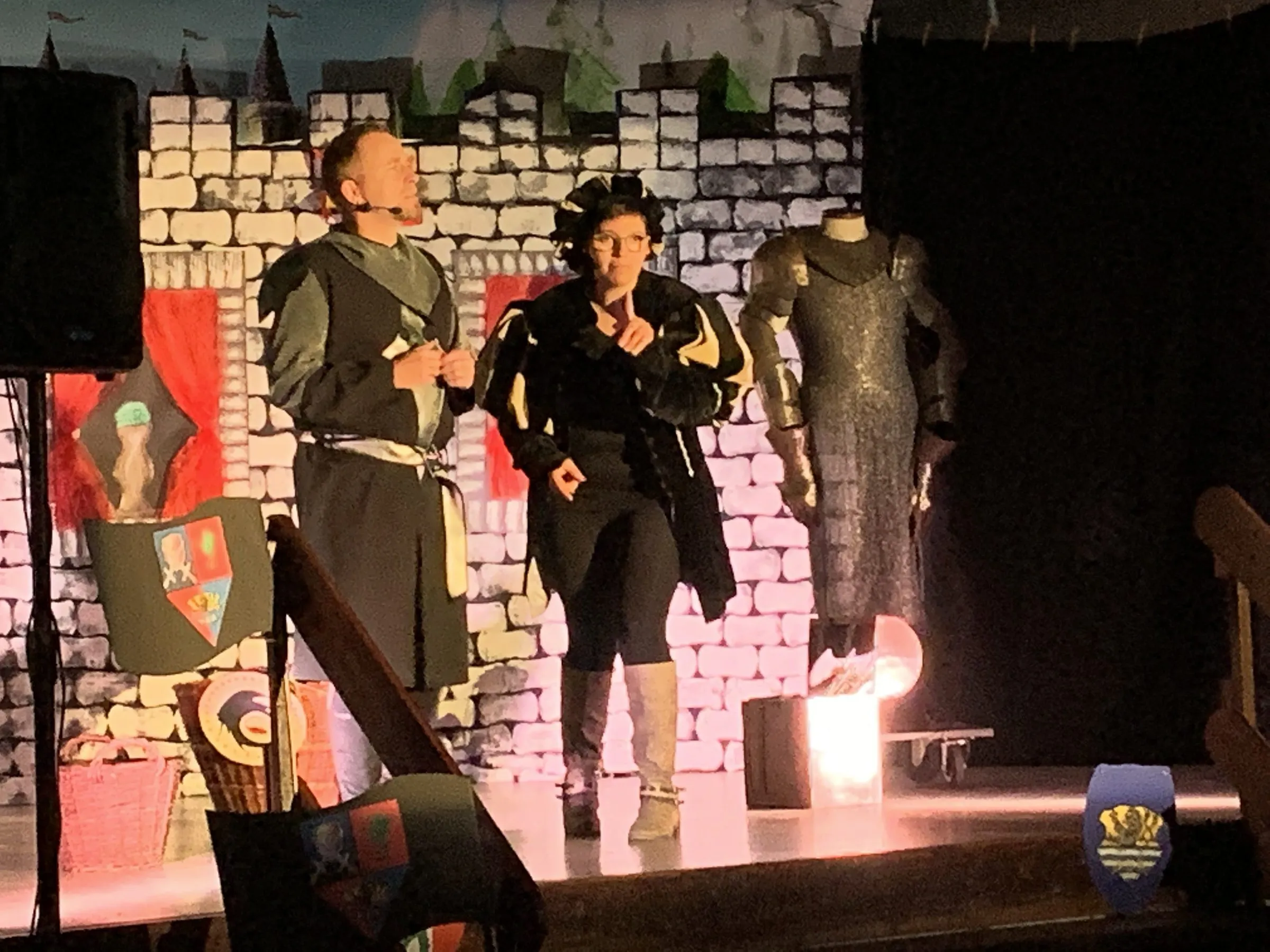 Ritter Veritas und Knappe Mathes vor der Burgkulisse, daneben eine Ritterrüstung auf einer Schneiderpuppe.