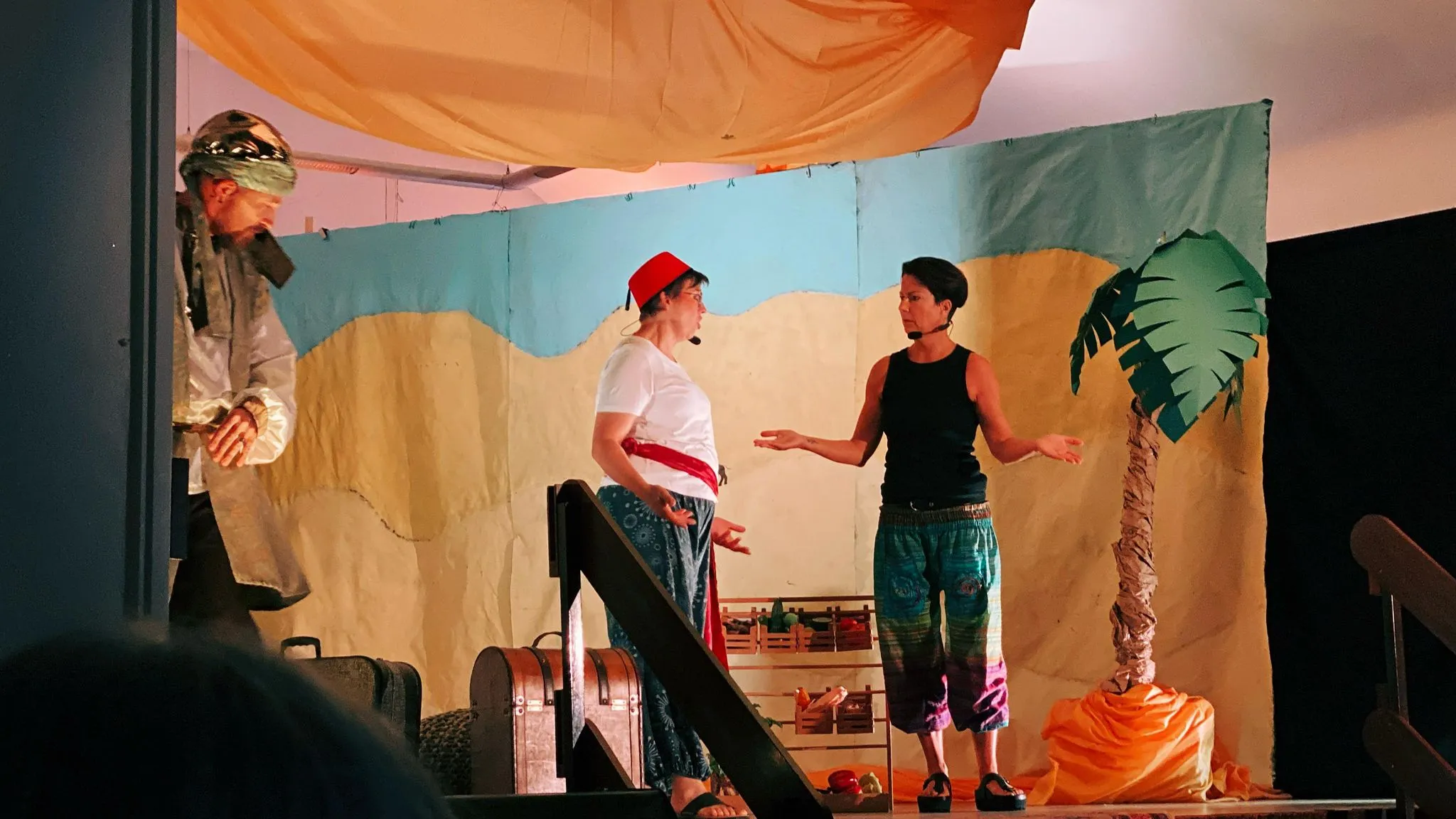 Eine Figur mit rotem Fes und der Wassermann im Gespräch mit dem Sultan vor der Kulisse.