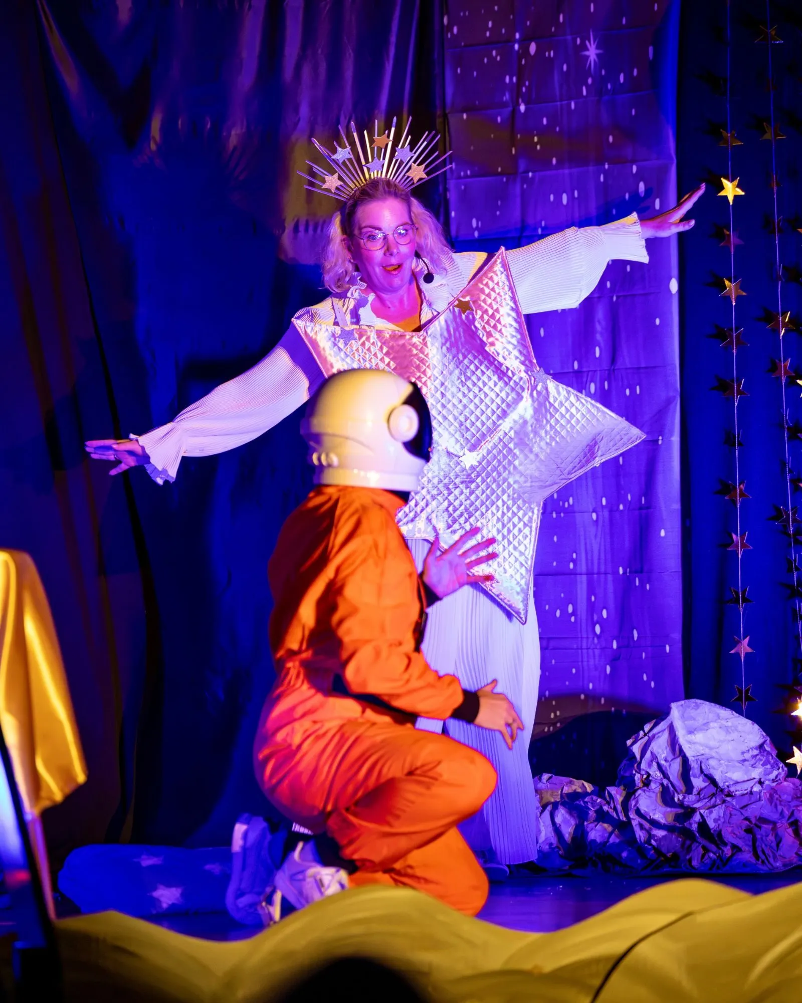 Stern Stella breitet die Arme aus und staunt über Edwin im Astronautenanzug mit Helm.