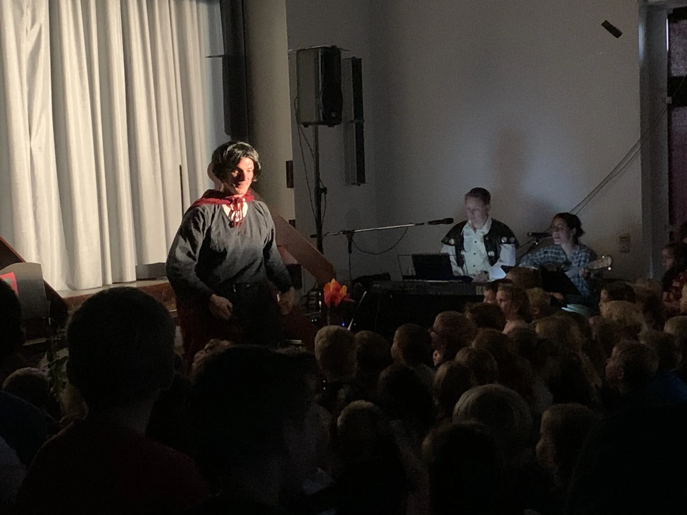 Rosemarie im Scheinwerferlicht vor dem Vorhang, im Hintergrund die Live-Musiker:innen an Keyboard und Gitarre.