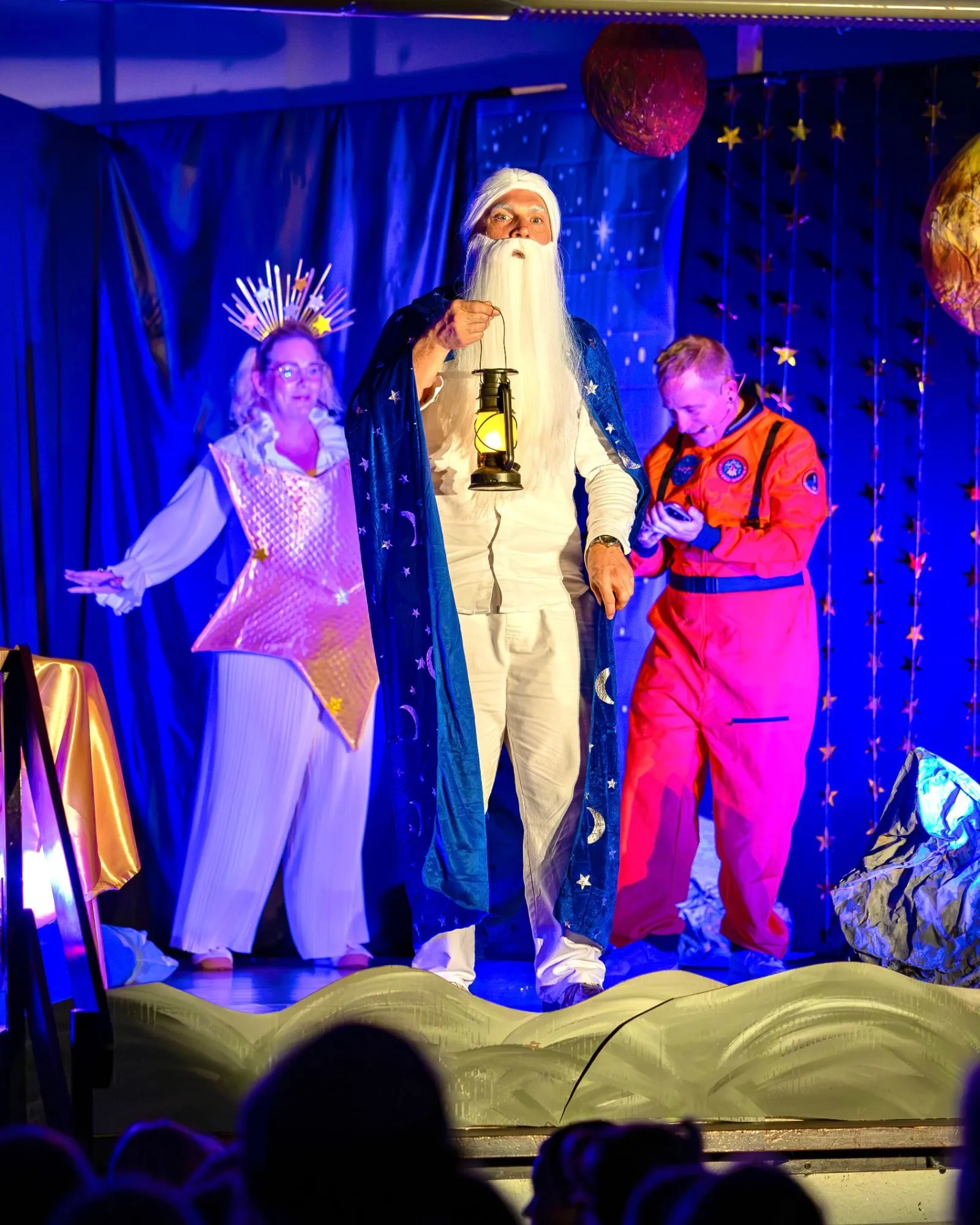 Der Mann im Mond mit Laterne in der Mitte, hinter ihm Stern Stella und Edwin, der auf sein Handy schaut.